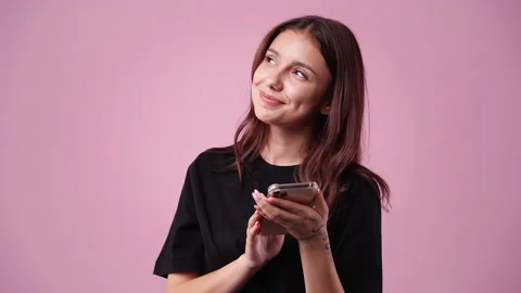 4k slow motion video of one girl using her phone over pink background. Video stock 228779725
