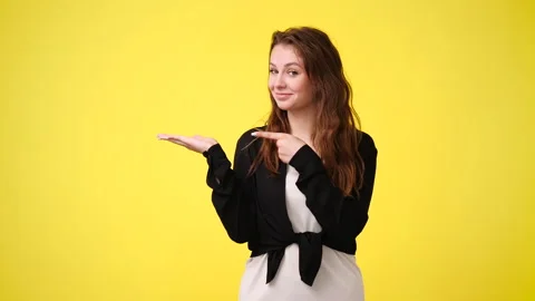4k slow motion video of one girl pointing at left over yellow background. Stock Footage 228988055