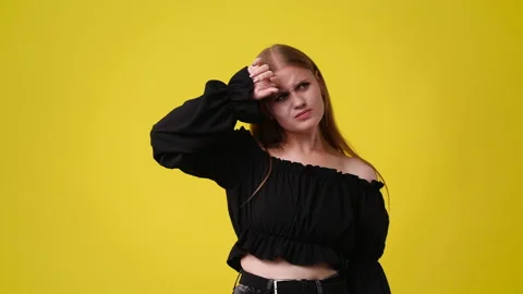 4k slow motion video of one girl with uncertain facial expression over yellow Stock Footage 229126513