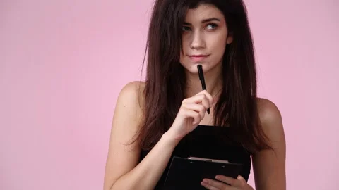 4k slow motion video of one girl taking down some notes over pink background. Stock Footage 229139820