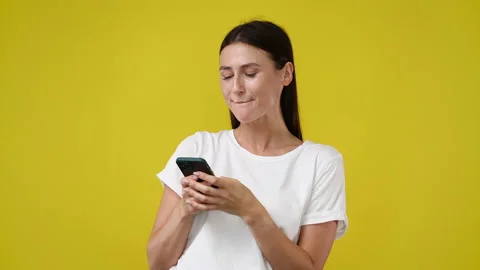 4k slow motion video of one girl using her phone over yellow background. Video stock 229297840