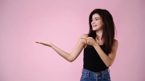 4k slow motion video of one girl pointing at left over pink background. Video stock 229651812