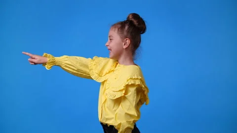 4k slow motion video of one girl pointing at left and smiling over blue Video stock 229662232