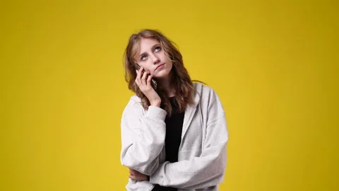 4k slow motion video of one girl talking over the phone on yellow background. Stock Footage 229777183