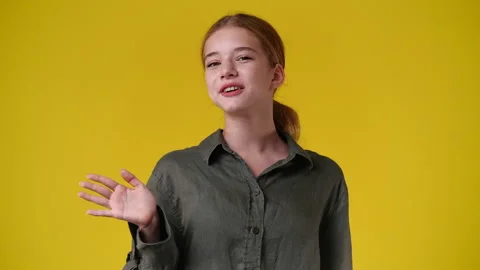 4k slow motion video of one girl waving hello on yellow background. Video stock 229998513