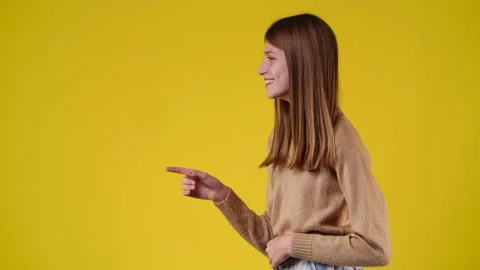 4k slow motion video of one girl pointing at left and laughing on yellow Video stock 230155183