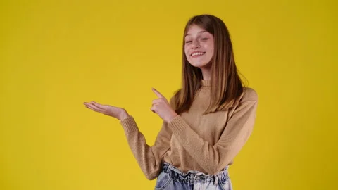 4k slow motion video of one girl pointing at left over yellow background. Stock Footage 230161225