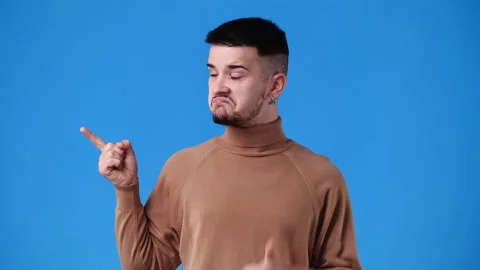 4k slow motion video of one man pointing at left and showing thumb up on blue Stock Footage 230177635