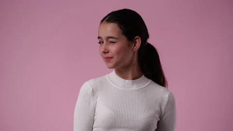 4k slow motion video of one girl blinking at the camera on pink background. Stock Footage 230257852