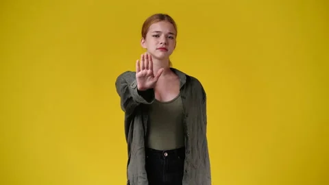 4k slow motion video of one girl showing stop sign over yellow background. Stock Footage 230272447