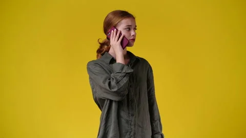 4k slow motion video of one girl talking over the phone on yellow background. Video stock 230402004