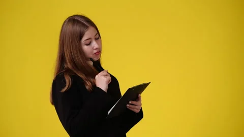 4k slow motion video of one girl taking notes over yellow background. Stock Footage 230409014