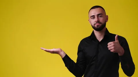 4k slow motion video of one man pointing at left and showing thumb up on yellow Video stock 230416385