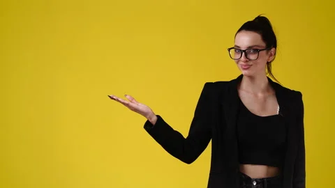 4k slow motion video of one girl pointing at left and showing thumb up on yellow Video stock 230653925