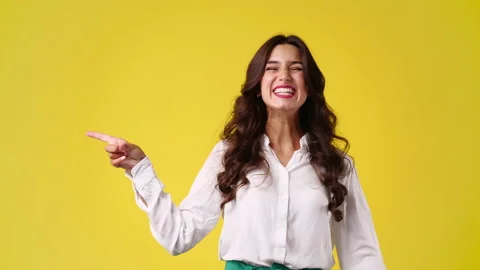 4k slow motion video of one girl pointing at left over yellow background. Stock Footage 231241933