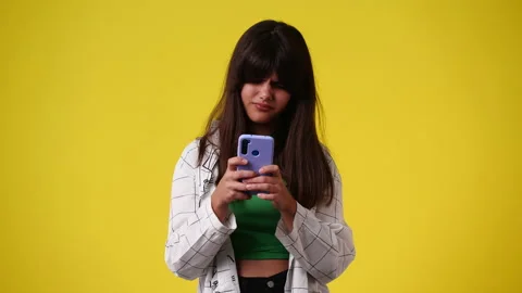 4k slow motion video of one girl using phone over yellow backgrpound. Video stock 231246106