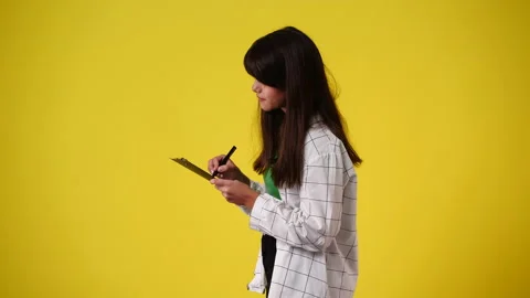 4k slow motion video of one girl taking notes over yellow background. Stock Footage 231247228
