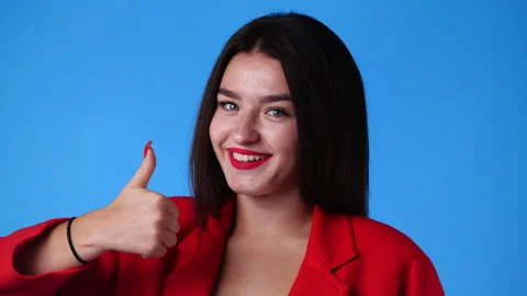 4k slow motion video of one girl smiling and showing thumbs up on blue Stock Footage 231406279