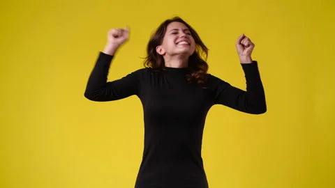 4k slow motion video of one woman emotionally rejoices over yellow background. Stock Footage 233120451