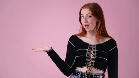 4k slow motion video of one girl pointing at left over pink background. Stock Footage 234310500