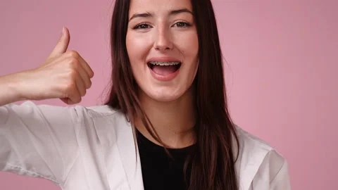 4k slow motion video of one girl showing thumbs up and smiling over pink Stock Footage 236570030