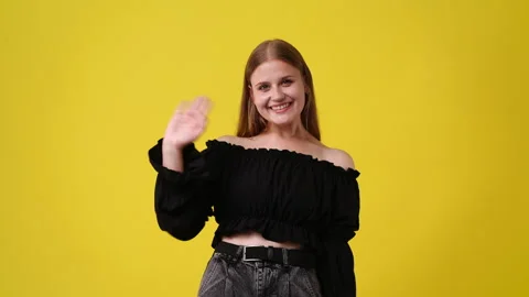 4k slow motion video of one girl says hello to someone over yellow background. Stock Footage 236652142