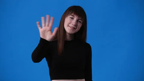 4k slow motion video of one girl says hello to someone over blue background. Stock Footage 237702326