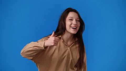 4k slow motion video of one girl showing thumbs up and smiling over blue Stock Footage 237754104