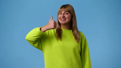 4k slow motion video of one girl smiling and showing thumbs up on blue Stock Footage 238037127