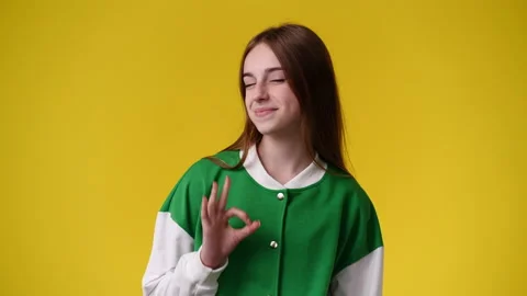 4k slow motion video of one girl showing OK sign and smiling over yellow Stock Footage 238445889