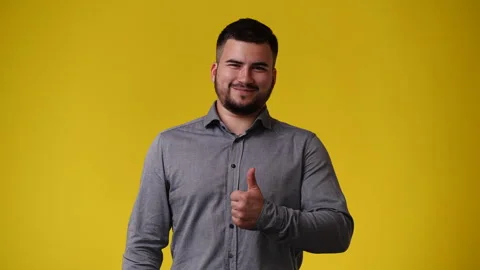 4k slow motion video of one man who showing thumb up sign over yellow background Stock Footage 241446176