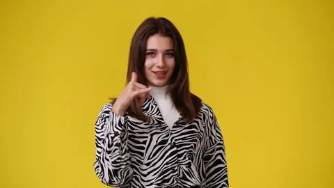 4k slow motion video of one girl asks to call someone over yellow background. Stock Footage 244304367