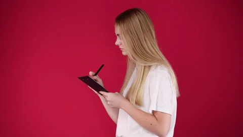 4k slow motion video of side view of one girl taking down some notes over pink Stock Footage 228718655