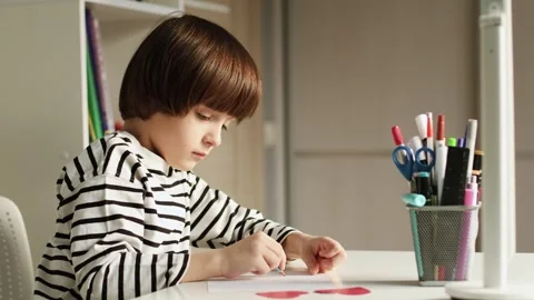 4K slow motion video of a young school boy studying and drawing at a desk at Stock Footage 327239399