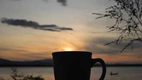 4K slow-motion view of a coffee cup placed by the water during sunrise Stock Footage 293257823