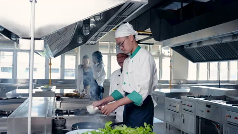 4K Slow, Two chefs are preparing a meal in kitchen in front of large gas Stock Footage 239003421