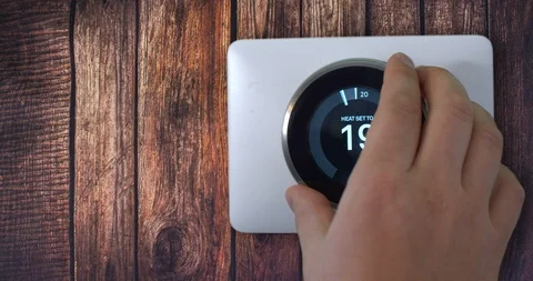 4k Smart Thermostat with a guy setting up the temperature on a wooden Stock Footage 120584812