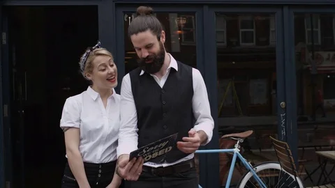 4K Smiling Bar Or Cafe Owners Hold Up A Sign To Show They Are Open For Business Stock Footage 75701182