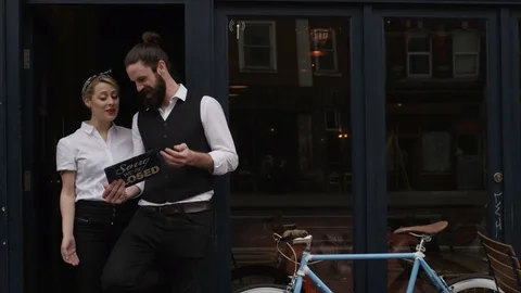 4K Smiling Bar Or Cafe Owners Hold Up A Sign To Show They Are Open For Business Stock Footage 75702709