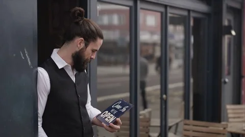 4K Smiling Bar Or Cafe Owner Holds Up A Sign To Show He Is Open For Business 動画素材 75704636