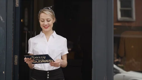 4K Smiling Bar Or Cafe Owner Holds Up A Sign To Show She Is Open For Business Stock Footage 75706100