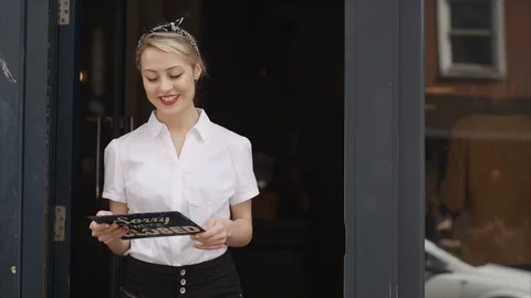 4K Smiling Bar Or Cafe Owner Holds Up A Sign To Show She Is Open For Business Stock Footage 75706104