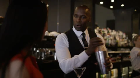 4K Smiling bartender prepares &amp; serves fresh cocktail for female customer Stock Footage 64695732