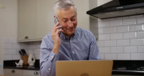 4K Smiling businessman at home working on laptop &amp; making a phone call Stock Footage 84133381
