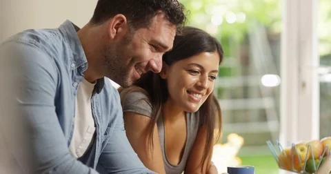 4K Smiling couple looking at laptop at home, reacting to what they see on screen Stock Footage