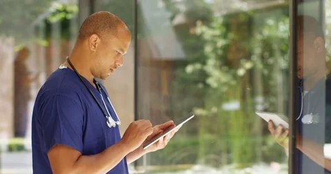 4K Smiling doctor with tablet in modern hospital with natural outdoor area Stock Footage 81177720
