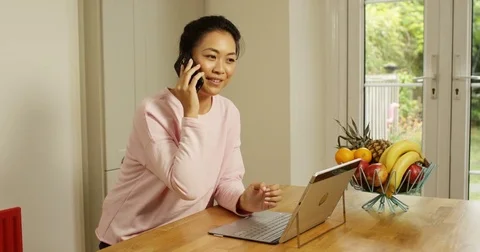 4K Smiling female entrepreneur using computer &amp; making phone call in home office Stock Footage 80449432