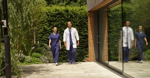4K Smiling medical workers walking together outside modern hospital building Stock Footage 81112177