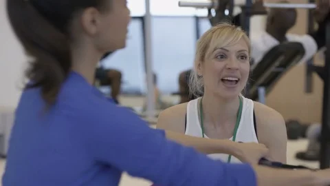 4K Smiling personal trainer helping clients to train in modern gym Stock Footage 75852426