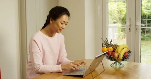 4K Smiling woman using digital tablet at home, swiping screen &amp; using keyboard Stock Footage 80516289
